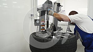 Auto tech swaps seasonal tires using modern machine in shop. Vehicle maintenance with tire changer, quick service for