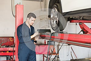 Auto Technician Making Checklist In Garage