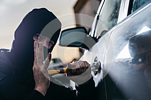 Auto thief in black balaclava trying to break into car