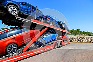 Auto transporter carries new cars of blue, red colors from the factory. Transportation of cars with specialized trucks
