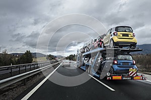 Auto transporter laden by small cars is on the highway