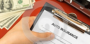 Auto and vechile insurance form in hand of man agent. Background of money and car toy. Banner photo