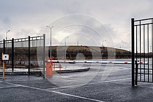 Automatic barrier of orange color with a white stripe and red warning stripes, for the entry of cars. Entrance to the