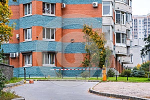 Automatic barrier of orange color with a white stripe and red warning stripes, for the entry of cars. Entrance to the courtyard of