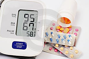 Automatic blood pressure meter and pills on white background