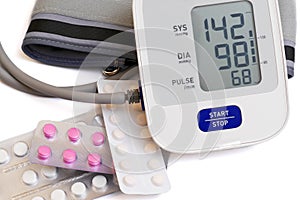Automatic blood pressure meter and pills on white background