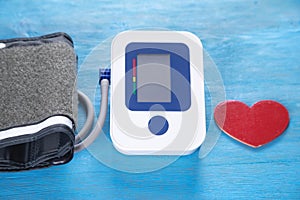 Automatic blood pressure meter and red heart on the blue background