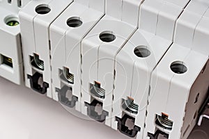 Automatic circuit breakers with disconnected ports installed on DIN rail in the white plastic mounting box closeup