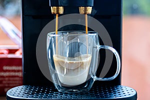 Automatic coffee machine brewing espresso into glass cup