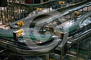 Automatic conveyor line or belt with glass bottles at brewery production. Industrial beer bottling equipment machinery