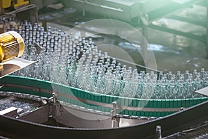 Automatic conveyor line or belt with glass bottles at brewery production. Industrial beer bottling equipment machinery