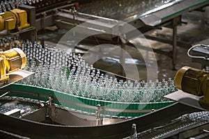 Automatic conveyor line or belt with glass bottles at brewery production. Industrial beer bottling equipment machinery