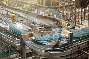 Automatic conveyor line or belt with glass bottles at brewery production. Industrial beer bottling equipment machinery