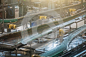 Automatic conveyor line or belt with glass bottles at brewery production. Industrial beer bottling equipment machinery