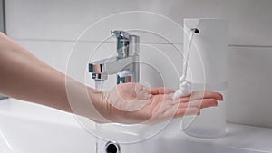 Automatic foam generator puts on hand the desired dose of soap. Modern technoloigia in the bathroom. Women`s hands