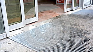 Automatic glass doors open and close. Entrance to the mall. Winter. Wet footprints on the floor. The legs of many