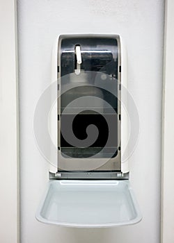 Automatic hand sanitizer dispenser on white wall