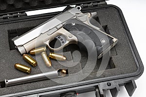 Automatic handgun and bullets in a plastic hard case on white background