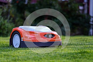 Automatic lawn robot mower moves on the short cut grass, lawn. Close up side view with blurry background