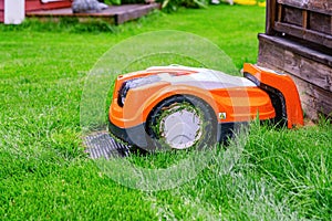 Automatic lawn robot mower under rain at charging stations on the grass, lawn. Close up side view with blurry background