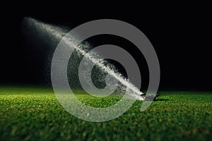 Automatic lawn sprinkler spraying water over golf course green grass