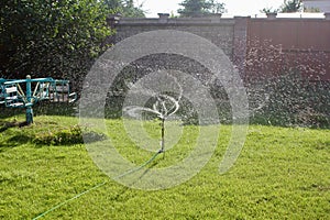 Automatic lawn sprinkler watering green grass. Sprinkler with automatic system. Garden irrigation system watering lawn