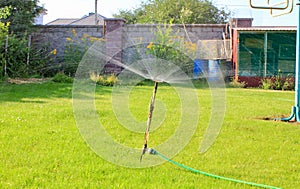 Automatic lawn sprinkler watering green grass. Sprinkler with automatic system. Garden irrigation system watering lawn