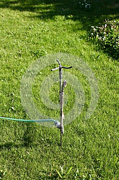 Automatic lawn sprinkler watering green grass. Sprinkler with automatic system. Garden irrigation system watering lawn