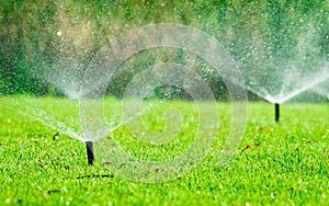 Automatic lawn sprinkler watering green grass. Sprinkler with automatic system. Garden irrigation system watering lawn. Water photo