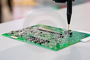 Automatic manipulator with dispenser needle during work with SMT pcb - close up photo