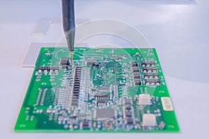 Automatic manipulator with dispenser needle during work with SMT pcb - close up photo