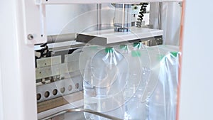 Automatic packaging of plastic bottles with film in the temperature press. Packaging of bottles for further