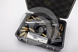 Automatic pocket handgun and bullets in a plastic hard case on white background