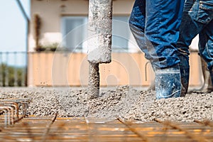 automatic pump tube working on construction site, workers directing and pouring concrete