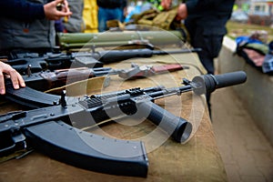Automatic rifle with a silencer on the table with weapons.