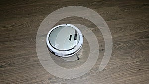 Automatic robot vacuum cleaner is white during operation. Cleans the floor. movement from left to right