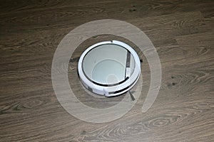 Automatic robot vacuum cleaner is white during operation. Cleans the floor. movement from left to right