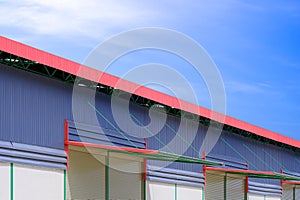 Automatic roller shutter doors with awning of modern rental warehouse building against blue sky background