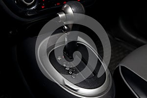 Automatic shift gear knob in the passenger compartment of the car in black for driving and acceleration. Abstract image of fast