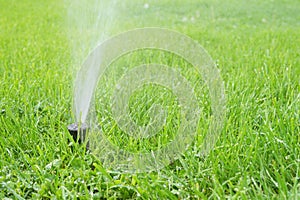 Automatic smart lawn sprinkler with adjustable head watering green lawn grass in sunny day