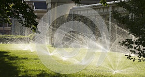 Automatic sprinkler system watering the lawn on a background of green grass
