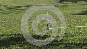 Automatic sprinkler that turns and sends water. Water a green lawn. Automated watering