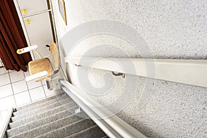 Automatic stair lift on staircase taking elderly people and disabled persons up and down in a house