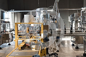 Automatic wine filling in bottles on metallic conveyer machinery at winery