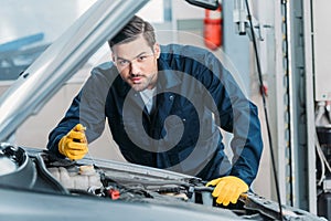 Automechanic looking under car hood