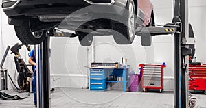 Automobil on lift for wheel suspension maintenance. Car service garage photo