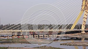 Automobile city traffic on the Signature cable-stayed bridge under construction over the Yamuna River in Delhi