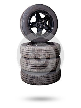 Automobile composition made up stack of tires and wheel with shiny black disc in the foreground against the background of cars in