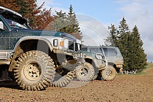 Automobile in a countryside landscape with a mud road. Off-road 4x4 suv automobile with ditry body after drive in muddy