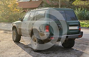 Automobile in a countryside landscape with a mud road. Off-road 4x4 suv automobile with ditry body after drive in muddy